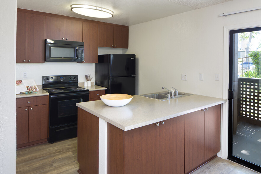 Kitchen with black appliances and hard surface vinyl plank flooring - eaves South Coast