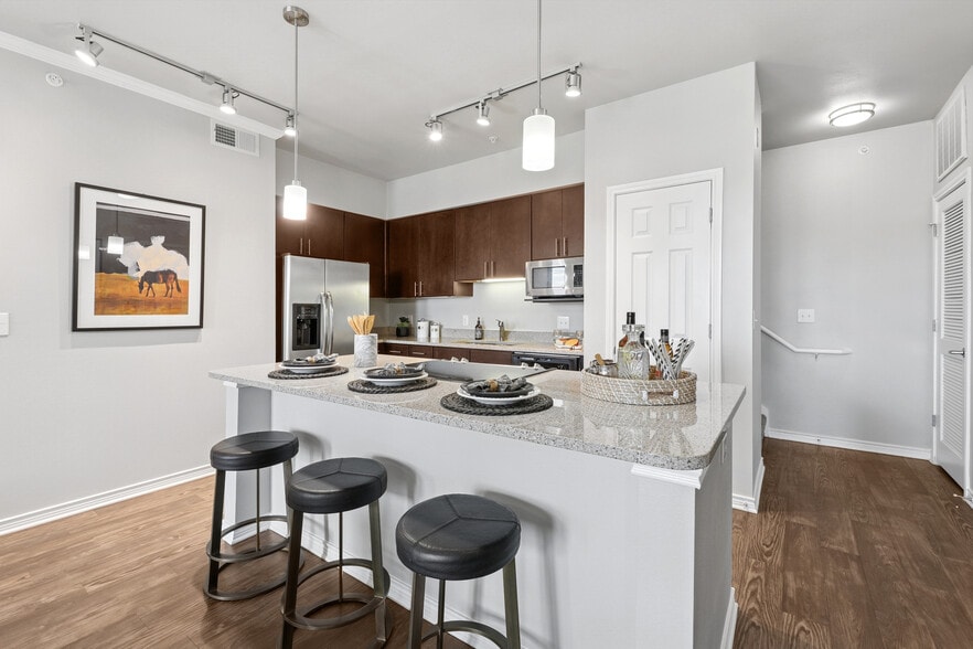 Kitchen with dark cabinetry, beige speckled granite countertops, stainless steel appliances, and hard surface flooring - Avalon Hill Country