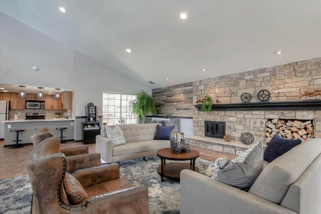 Image of the resident club house with couches, a table, a fireplace, and a view of the kitchen. - Chestnut Ridge Apartment Homes