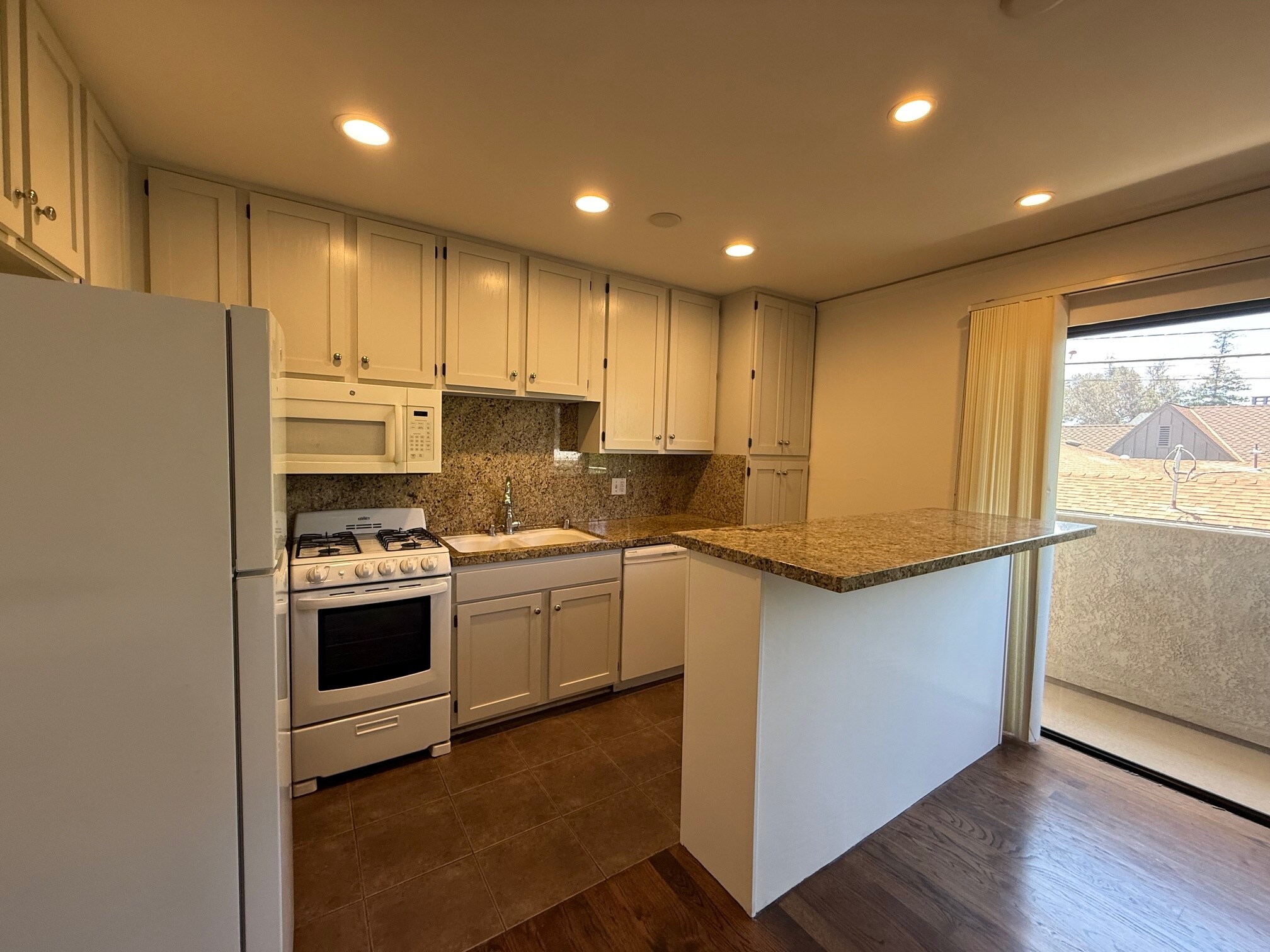 Kitchen with stove, microwave, dishwasher, refrigerator + granite counter tops and breakfast bar - 10330 Riverside Dr