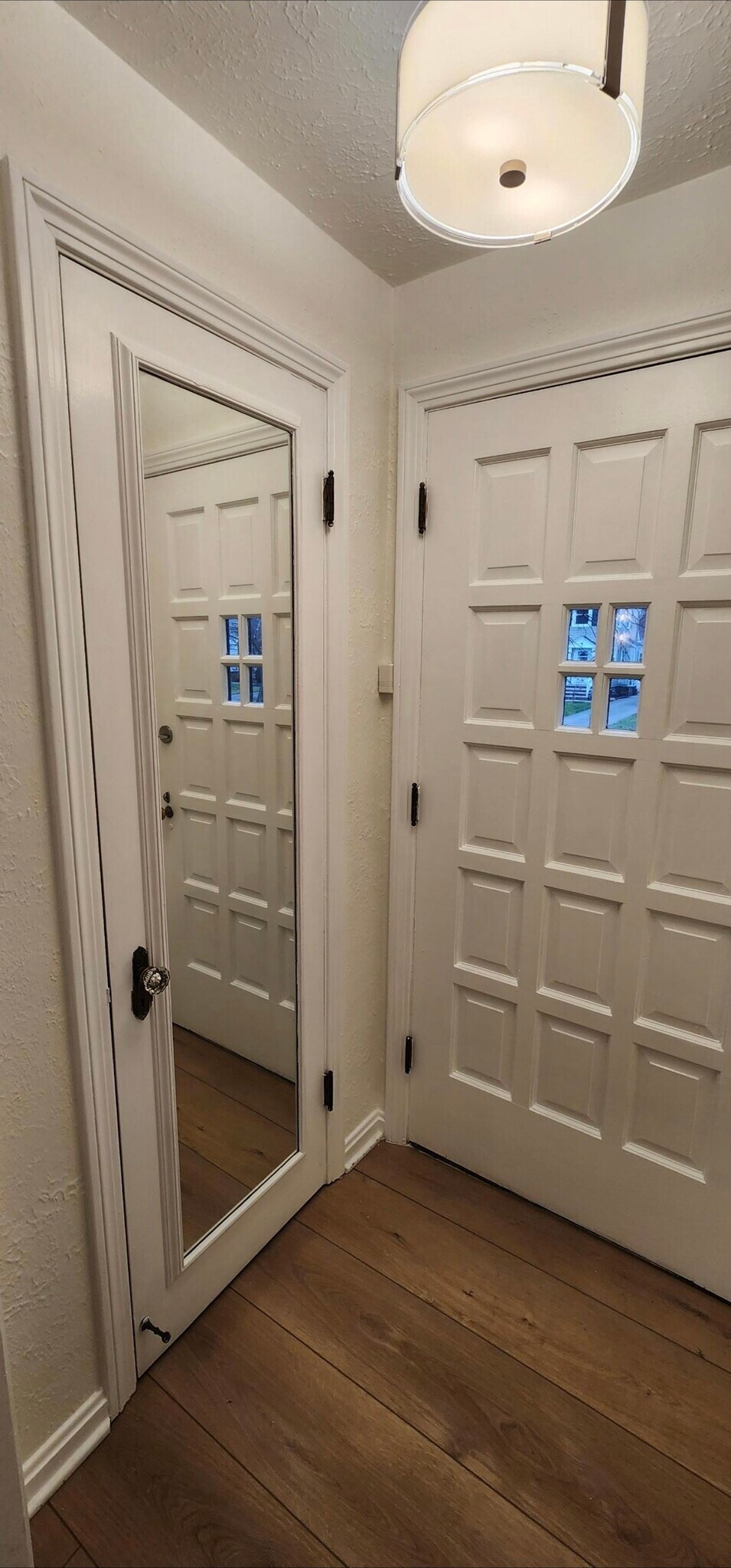 legant entryway featuring custom paneled doors with decorative glass insets, full-length mirror, mod - 90 E 216th St