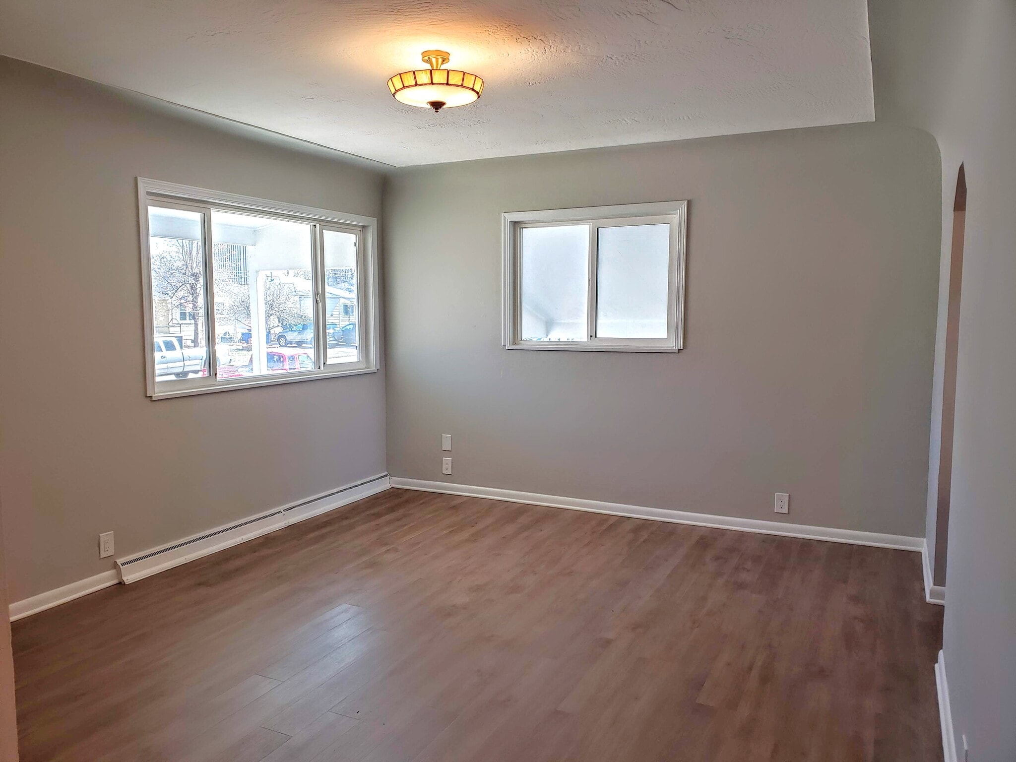 Living room full of charm from coved ceilings, luxury vinyl plank flooring, and a vintage light! - 3155 S Fox St