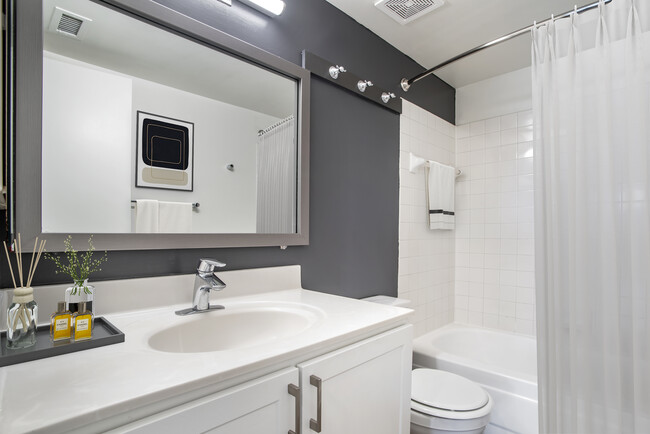 Renovated Package II bath with white countertops and cabinetry, accent wall, and hard surface flooring - AVA Ballston