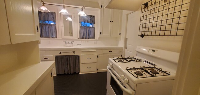 Kitchen has cabinets and long counters for meal prep. Gas range with wall rack for pots and pans - 1229 N Orange Grove Ave