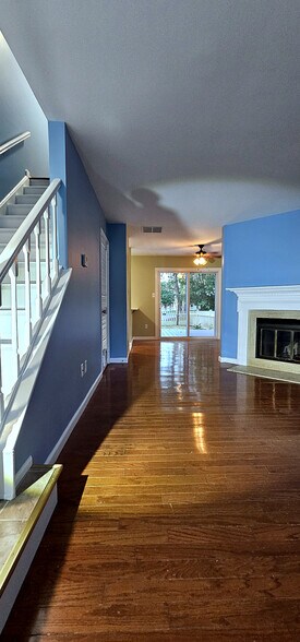Gracious Entry Hall | Hardwood hallway with a striking navy accent wall connects the foyer - 43 Tynemouth Ct