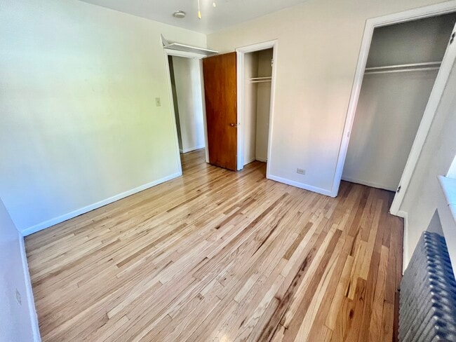 Embrace serenity in this well-lit bedroom featuring polished wood flooring. - Hillside Apartments