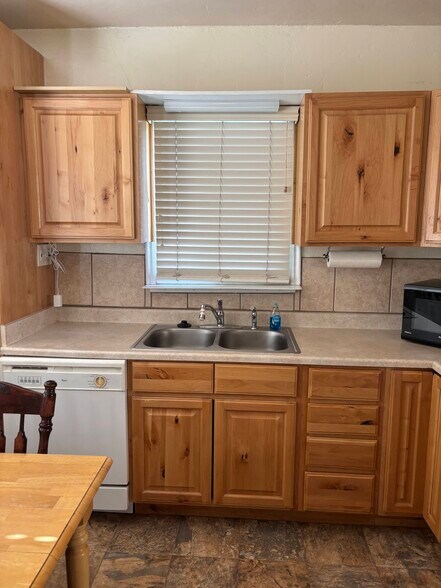 The kitchen features warm natural wood cabinetry, a double sink, tiled backsplash, and a built-in Wh - 290 N 300 E