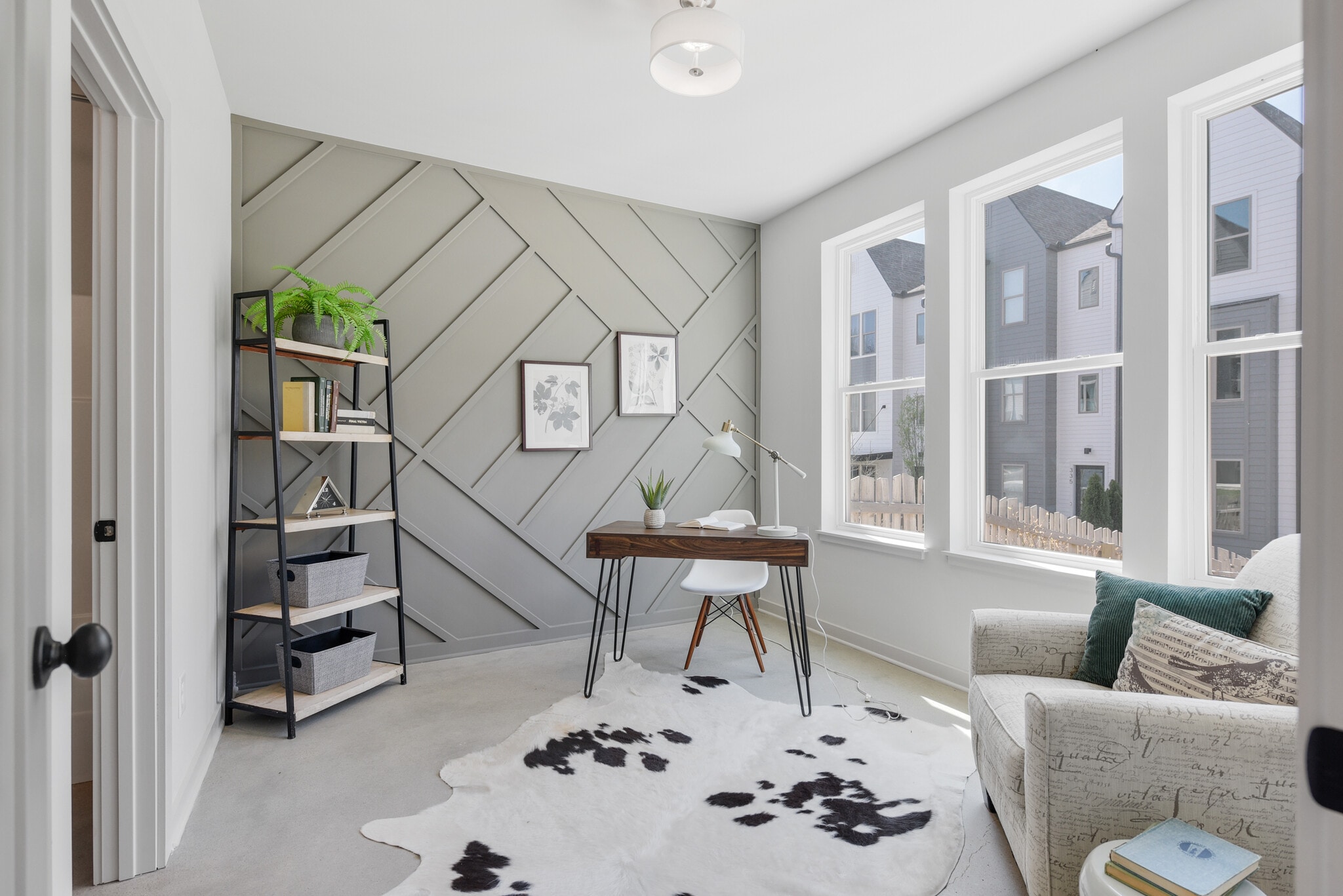 Sunlit first-floor bedroom with oversized windows and modern feature wall. - 358 E Village Ln
