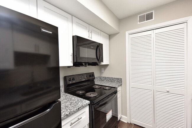 Kitchen with granite counters, modern cabinetry, and black appliances - Harpeth Trace