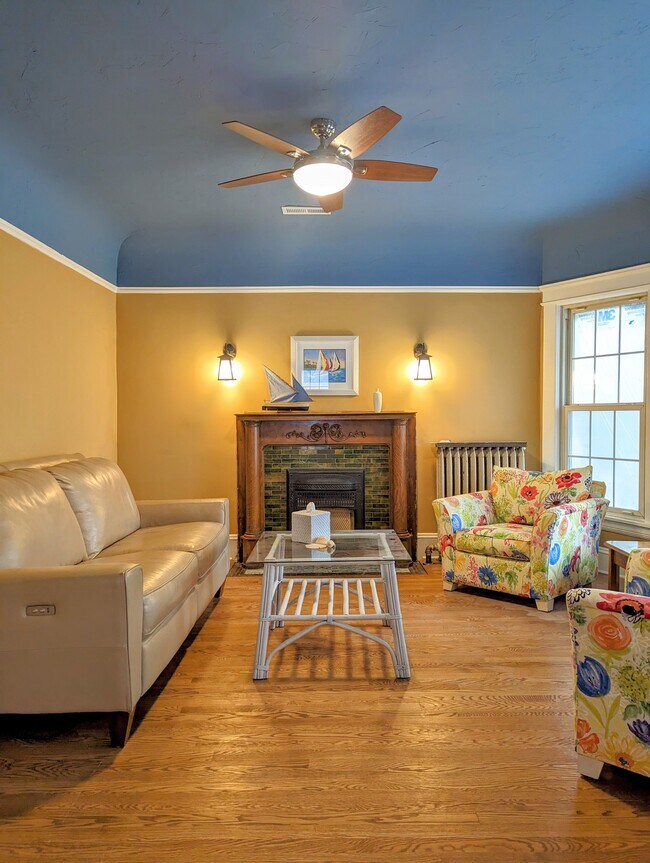 Living room with leather couch, coffee table, decorative fireplace, TV, bay window - 7216 W Clinton Ave