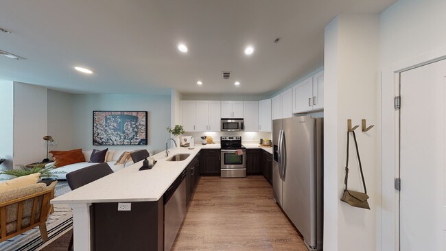 Open kitchen meticulously reimagined with two-tone cabinets, quartz counters, and stainless steel appliances - Alister Montclair