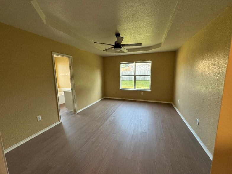 Spacious primary bedroom with tray ceiling and backyard view. - 2806 Maria Dr