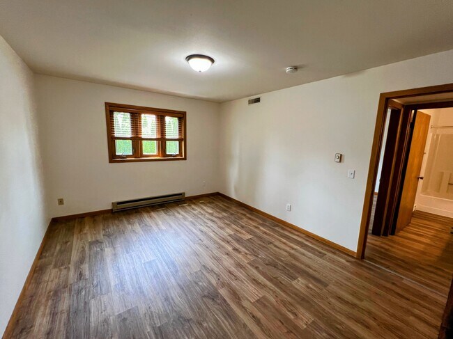 primary bedroom with wood-style floors, large window, and plenty of space for a queen or king bed - 213 Ash Street