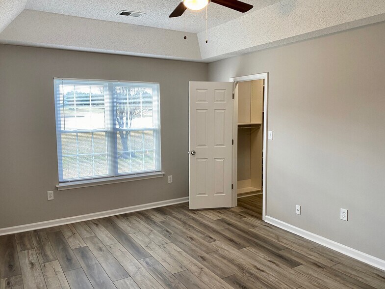 Large master bedroom with expansive master bathroom, walk-in closet including built in organization shelves, ceiling fan, and tranquil views of the backyard and pond with fountain! - 1914 Conifer Cir