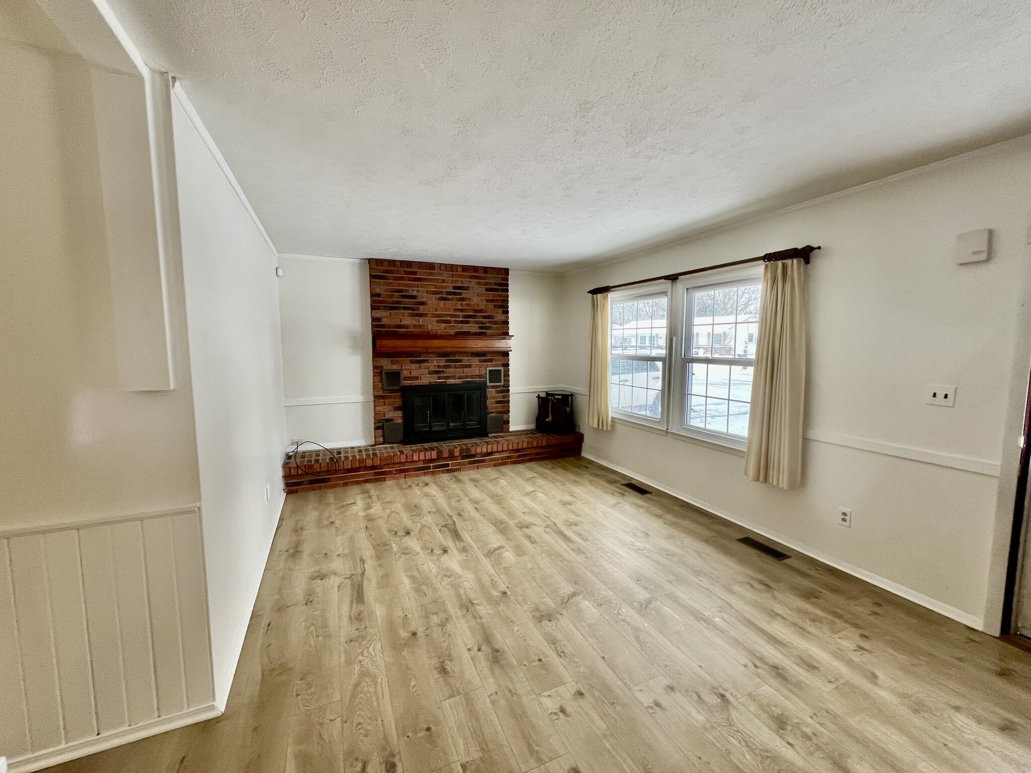 Living room with new Mohawk vinyl plank flooring and wood fireplace - 1201 Hollyview Dr