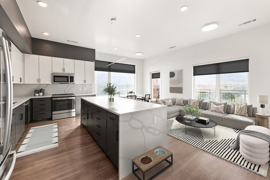 Modern open-concept kitchen and living area with sleek cabinetry, a spacious island, and panoramic window views. - Dorian
