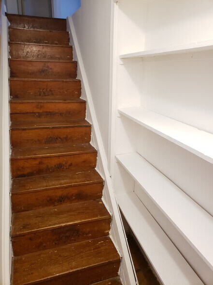 Off of the living room are display shelves and the original wood stairway to the second floor. - 10106 Wingfield Rd