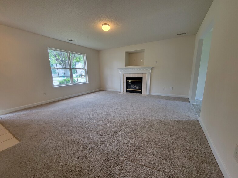 Spacious living room with a gas fireplace and built-ins for a television. - 6903 Seney Dr