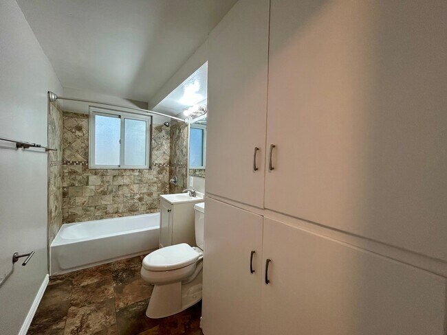 Contemporary bathroom with elegant tile design, bathtub, and ample storage, offering a serene and functional space. - Boardwalk Apartments