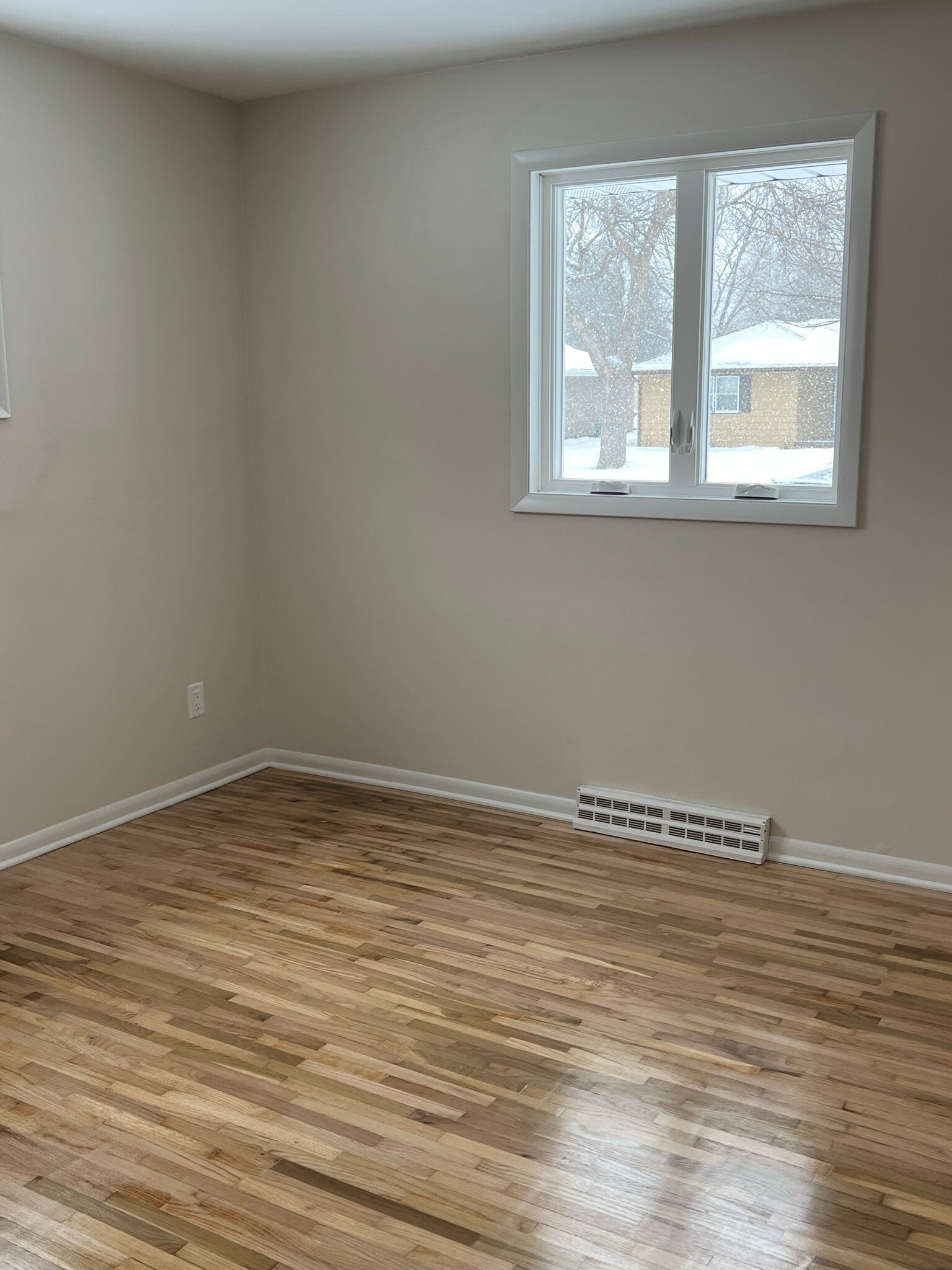Bedroom 1 with new windows, paint, and refinished flooring in 2023 - 835 Maple St NE