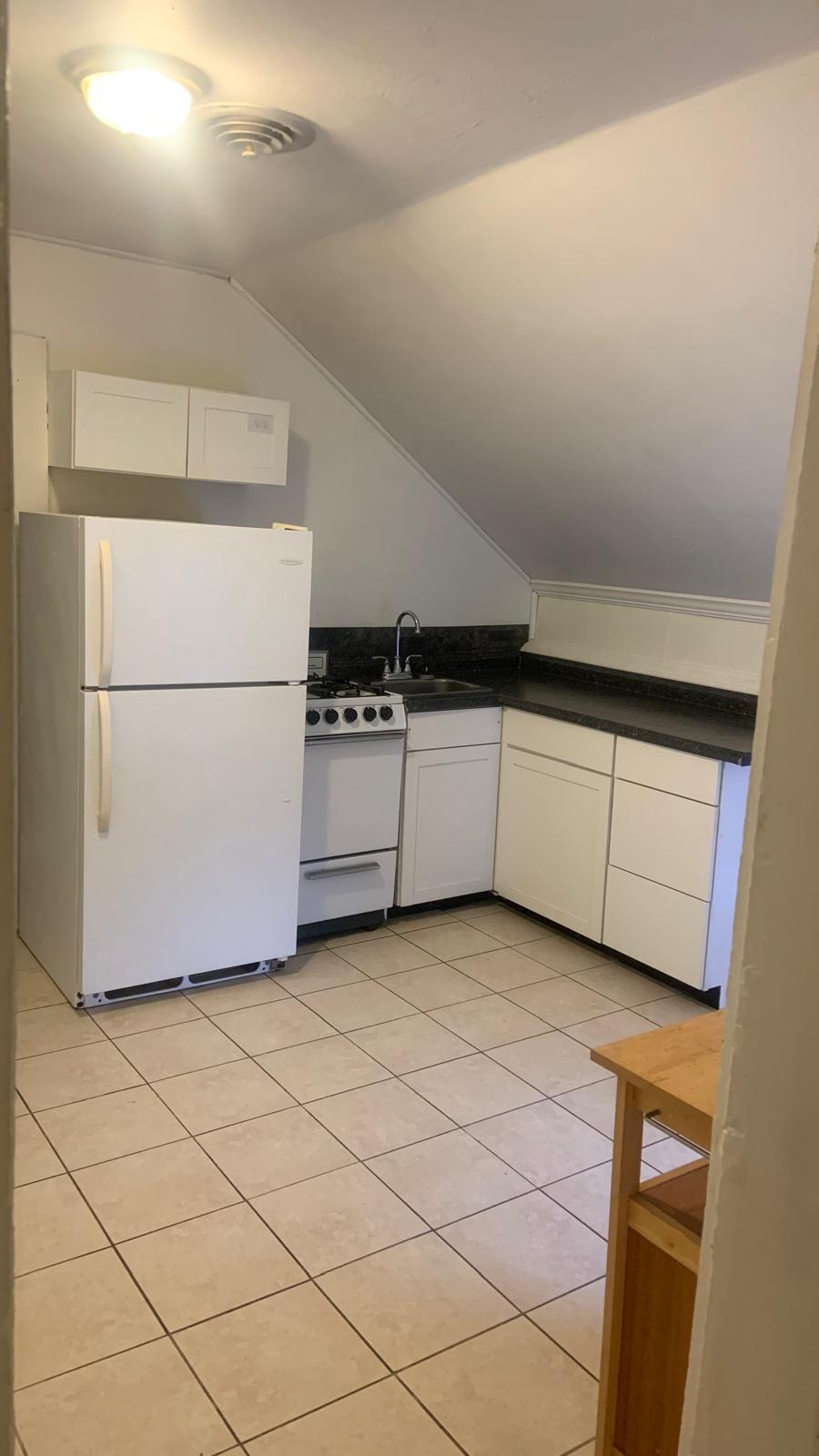 Kitchen equipped with a stove, refrigerator, and cupboards. - 21 Gage Ave