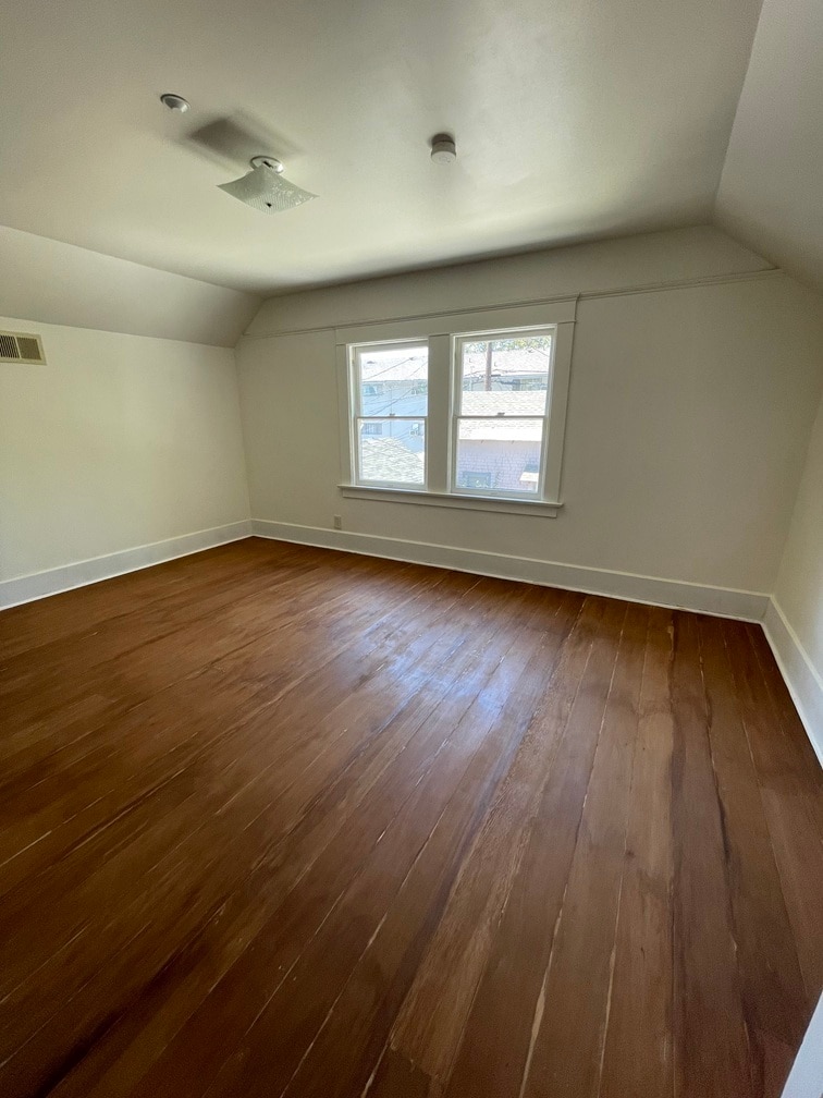 Fifth bedroom with an adjacent walk-in closet. Hardwood floors before clear varnish application. - 1135 Magnolia St