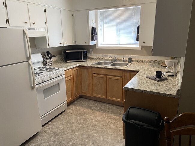 Kitchen with gas stove, fridge, micro wave, coffee maker, toaster, pots pans, plates and utensils. - 1000 10th Ave NW