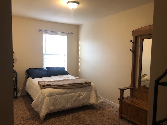 Bedroom 1 shown with furniture. - 1220 W Bismark Ave