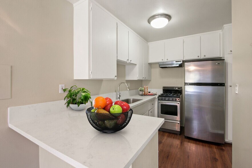 Kitchen with stainless steel two-door refrigerator, gas stove over range hood, white cabinets - Seville Townhouse