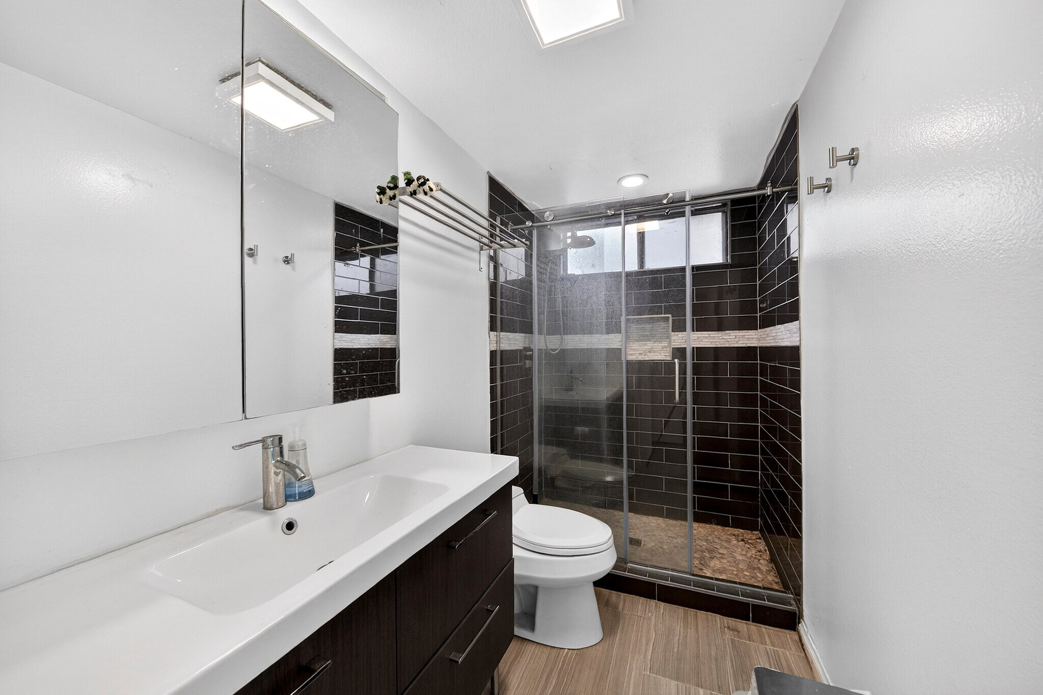 The primary ensuite features a striking walk-in shower clad in subway tile and pebble floor - 5214 Dawes Ave