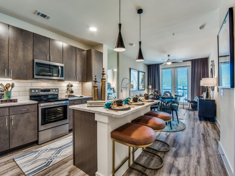 Kitchen with espresso cabinetry, speckled granite countertops, white subway tile backsplash, stainless steel appliances, and hard surface flooring - Avalon Castle Hills