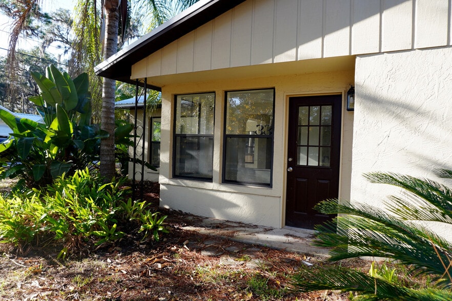 Welcoming front with dark door and tropical plants—serene entry to Nature Coast life. - 33 63rd St