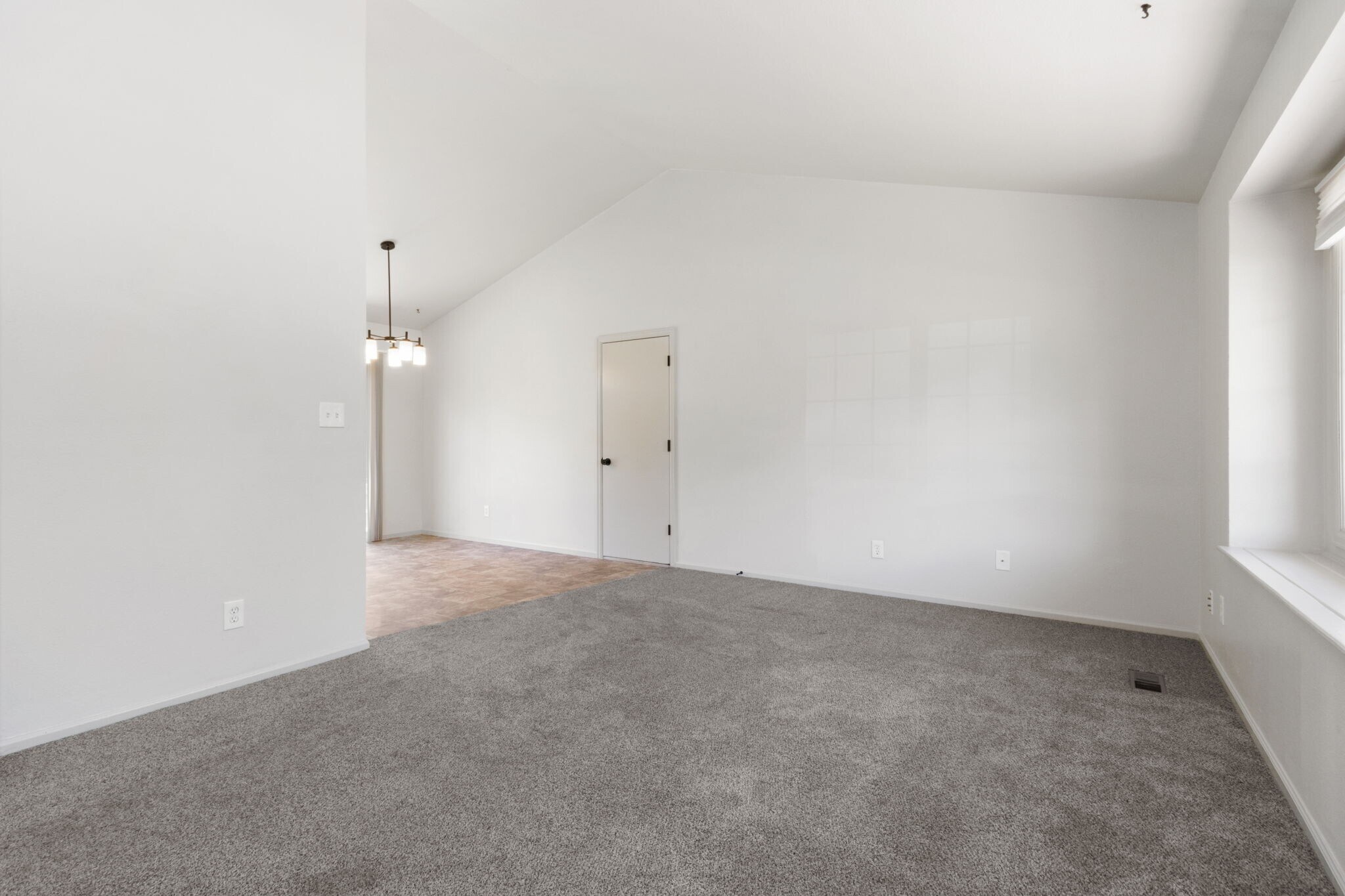Vaulted living room. Door to attached 2-car garage. - 1956 Promenade Way