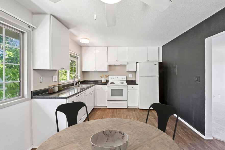Kitchen with white cabinetry, black laminate countertops, white appliances, and hard surface flooring - AVA Newport