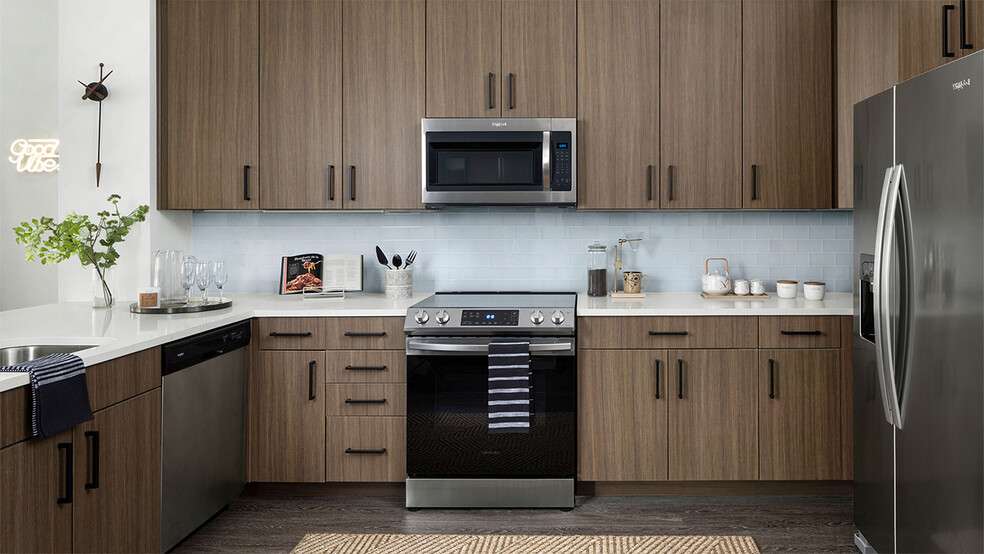 Apartment Kitchen with Stainless Steel Appliances, quartz countertop and hardwood flooring. - Griffis Cherry Creek North