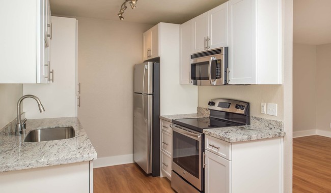 Modern kitchen with stainless steel appliances and granite countertops - Pacifica Park Apartments