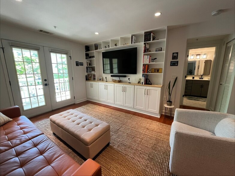 Living area with custom built-ins and doors to a private balcony. - 4079 S Four Mile Run Dr