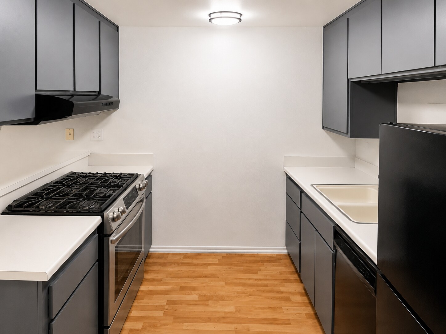 Clean galley-style kitchen with gray cabinetry, light countertops, wood-look flooring, and updated a - 339 E Taft Ave