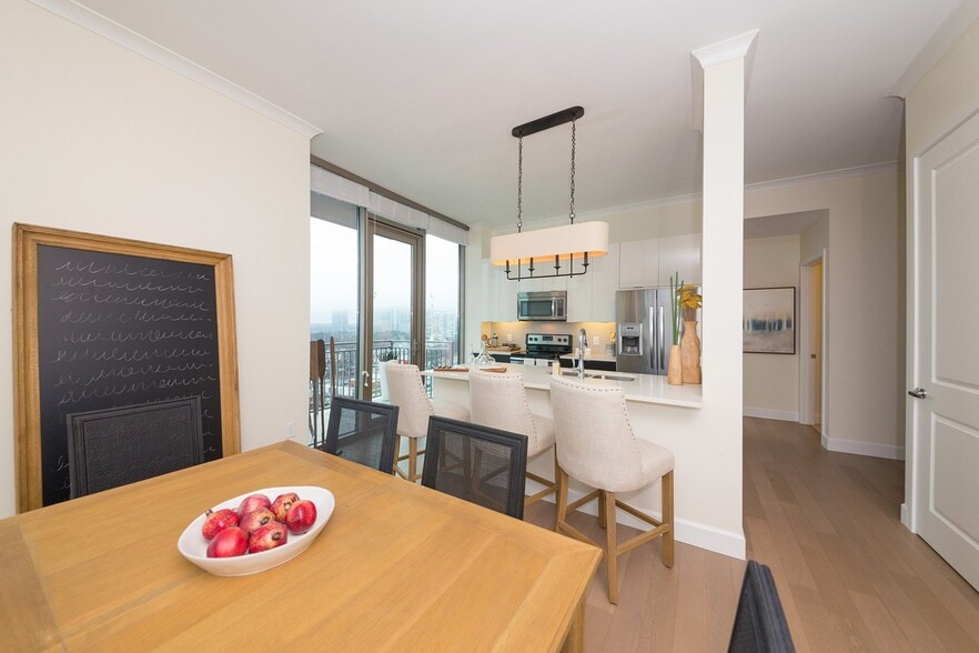 Floor-to-ceiling windows bring in abundant daylight and frame skyline views from this bright dining setting - The Residence Buckhead Atlanta
