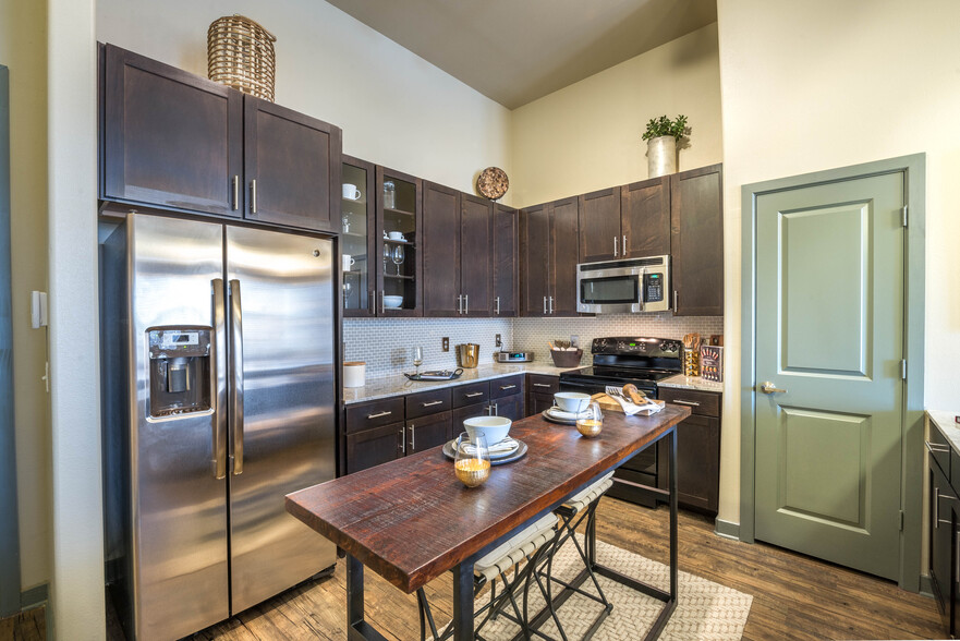 Kitchen with espresso cabinetry, tile backsplash, granite countertops, and stainless steel appliances - Avalon Lakeside