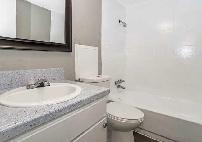 Clean bathroom with full tub/shower combo and updated countertop. - Sierra Nevada Apartments