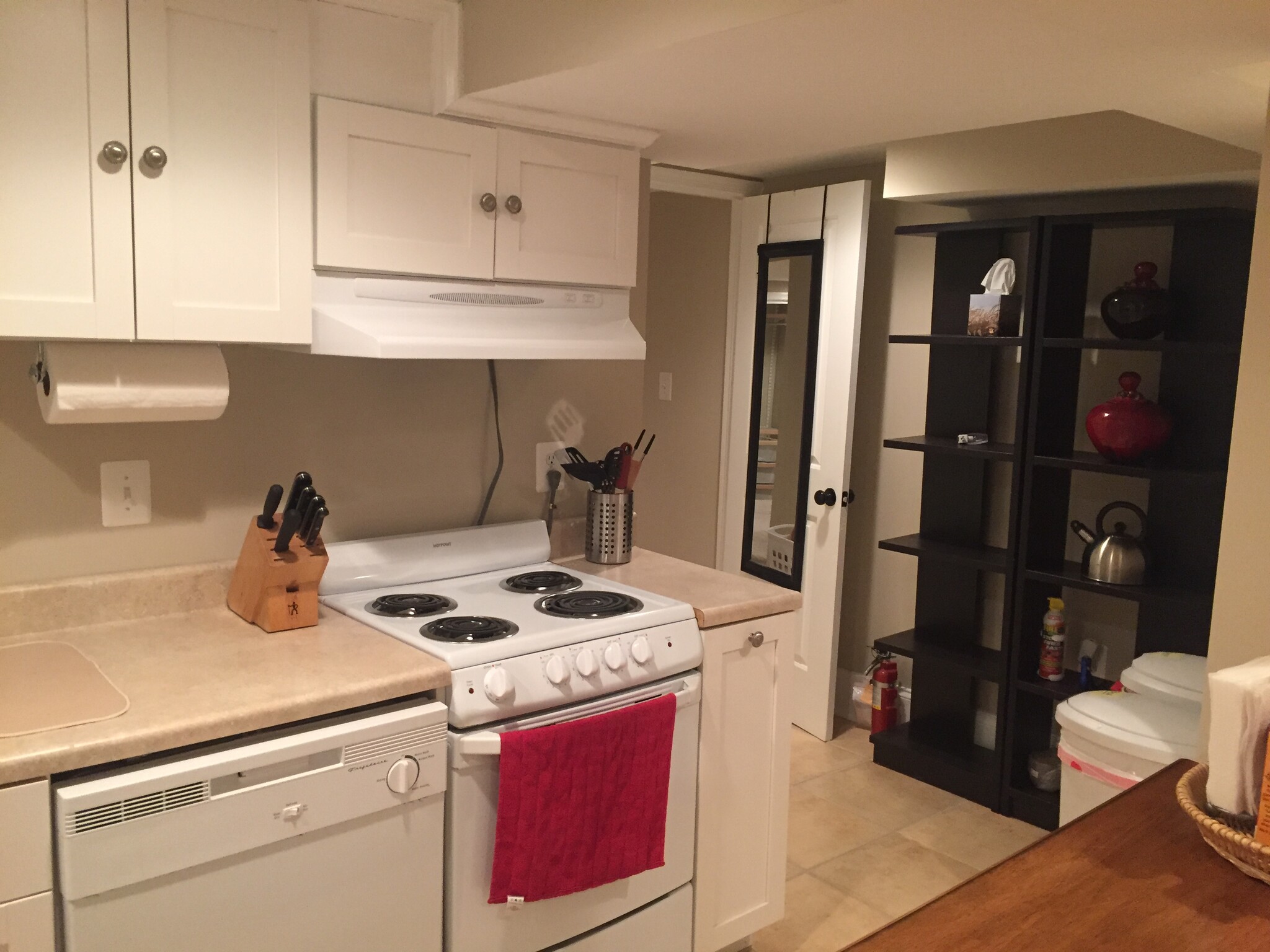 Fully furnished open kitchen with dishwasher, microwave, stove, range, island with seating for 2 and extra storage, bookshelves for extra storage, and trash/recycling bins - 43 Girard St. NE