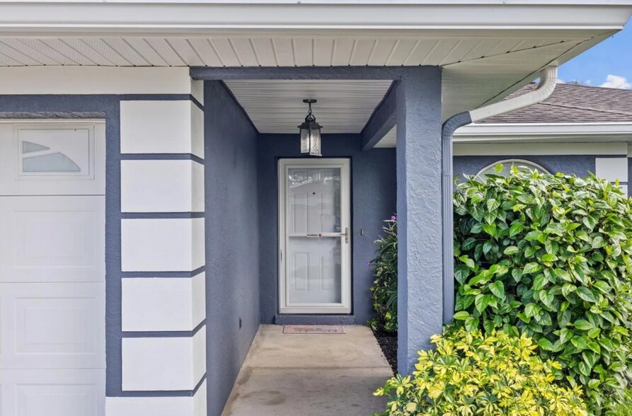 Cozy front porch entry with covered space and lush landscaping. - 1932 Brainerd Ct