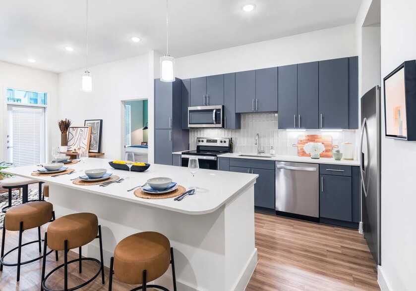 Indulge in culinary delights within Modera Garden Oaks' gourmet kitchens, highlighted by quartz countertops and custom 42-inch cabinetry featuring under-cabinet lighting for both style and practicality. - Modera Garden Oaks