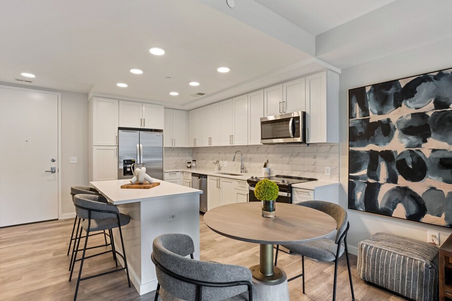 Gourmet Kitchen And Dining Area With White Countertops, Pearl Paneled Cabinets, and Stainless-Steel Appliances - High Street Atlanta