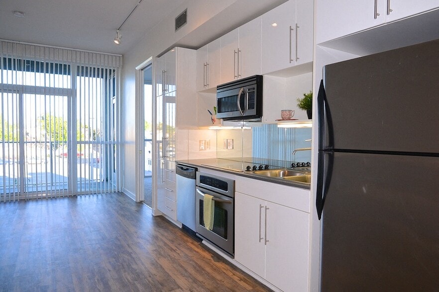 Kitchen with hardwood floors, stainless steel apliances and patio access at 12th Street Lofts in National City, California. - 12th Street Lofts
