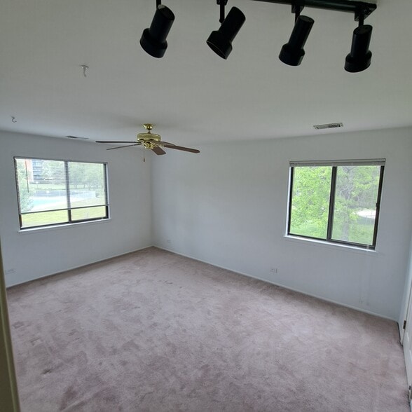 spacious master bedroom with two windows with nature views and celing fans and track lighting - 226 Arrowwood Ct