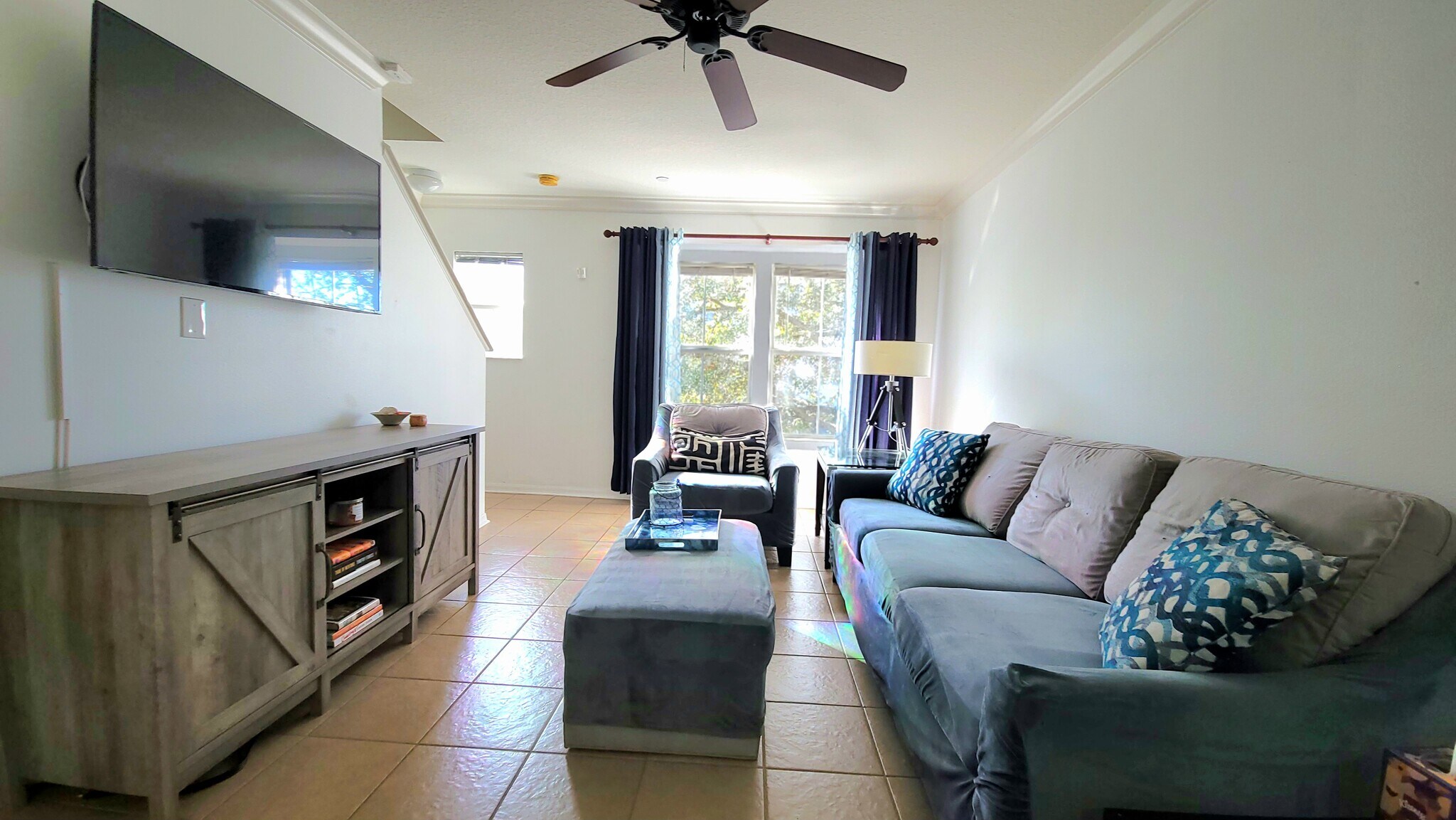 The living room is equipped with a comfortable sofa, oversized chair, ceiling fan, and smart TV! - 4408 Tuscan Loon Dr