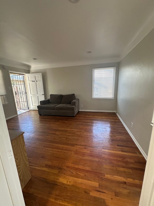 Bright main living space with warm wood flooring - 5646 Farmdale Ave