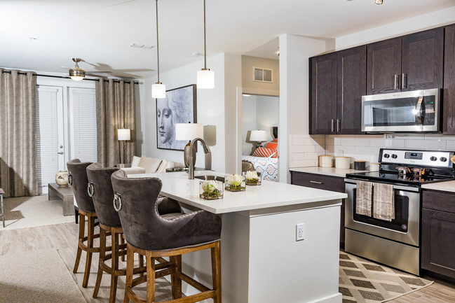 Beautifully decorated model apartment kitchen with barstool seating, shaker style kitchen cabinets, quartz countertops and stainless steel appliances - The Haven at Indigo Square